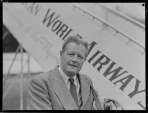 Portrait of E Villen, Readers Digest Representative, in front of a Pan American Airways plane, Whenuapai Airfield, Auckland