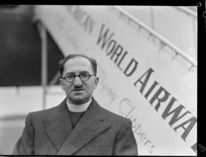 Portrait of Reverand A Aston in front of a Pan American Airways Clipper Class passenger plane boarding ramp, Whenuapai Airfield, Auckland