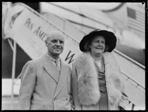 Portrait of Mr & Mrs E H Scott in front of a Pan American Airways Clipper Class passenger plane boarding ramp, Whenuapai Airfield, Auckland