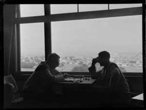 View of two unidentified men playing a game of draughts, the Blind Institute Building, [Auckland?]