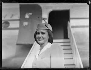 Portrait of Miss Hope Parkinson, a Pan American World Airways (PAWA) Air Hostess in front of a PAWA passenger plane,[Whenuapai Airfield, Auckland?]