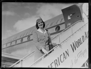 Portrait of Miss Hope Parkinson, a Pan American World Airways (PAWA) Air Hostess, descending boarding stairs from a PAWA Clipper passenger plane, [Whenuapai Airfield, Auckland City?]