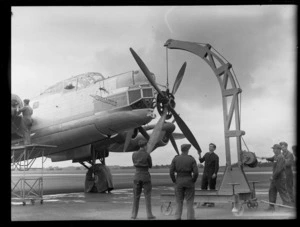 A group of unidentified men using a moblie crane to take the propellor off the Avro Lincoln bomber aircraft Excalibur, at Whenuapai Airbase, Auckland