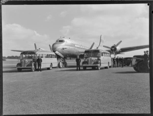Pan American World Airways Douglas Clipper 'Kit Carson' NC88881, on tarmac with two Johnston's Airways Transport buses and unidentified members of staff alongside, RNZAF Station, Whenuapai, Auckland