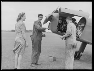 Miss Emily Restall, with two unidentified men who are working on the engine of an aeroplane, at Auckland Aero Club, Mangere, Auckland