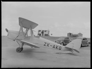 De Havilland DH 82 Tiger Moth biplane, ZK-AKO, at Auckland Aero Club, Mangere, including wooden [club?] building in background