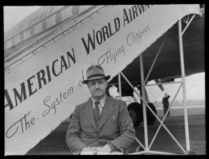 Portrait of Cyril Sanders in front of a Pan American Airways Class passenger plane boarding ramp, Whenuapai Airfield, Auckland