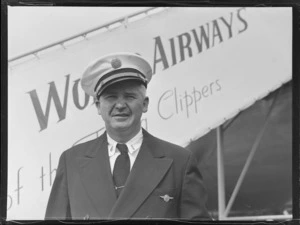 Portrait of Captain B G Blackmore of PAWA in front of a Pan American Airways Clipper Class passenger plane boarding ramp, Whenuapai Airfield, Auckland