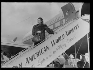 Portrait of actress Tara Barry, in front of a Pan American Airways Clipper Class passenger plane boarding ramp, Whenuapai Airfield, Auckland