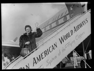 Portrait of actress Tara Barry, in front of a Pan American Airways Clipper Class passenger plane boarding ramp, Whenuapai Airfield, Auckland