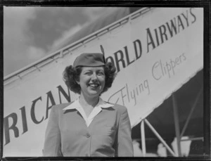Portrait of PAA Stewardess Mary Jean O'Donald in front of a PAA Clipper Class passenger plane at Whenuapai Airfield, Auckland