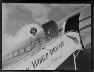 Portrait of PAA Stewardess Mary Jean O'Donald on a gangway of a PAA Clipper Class passenger plane at Whenuapai Airfield, Auckland