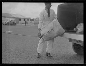 An unidentified airport employee loading US mail on to a truck, Whenuapai Airfield, Auckland