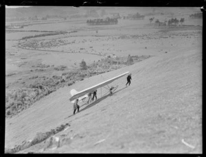 Men from the Auckland Gliding Club pulling a Alfriston primary glider, up a mountain hill, location unknown