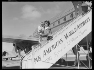 Stewardess Mary Lyman holding toddler, disembarking from aircraft PAWA (Pan American World Airways) Clipper Kit Carson