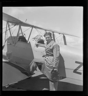 Portrait of photographer H Paton of 'K-20' fame holding an aerial camera next to a Tiger Moth bi-plane, location unknown