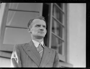 Portrait of E H Neal, ex Qantas Empire Airways (QEA) pilot, in front of an unknown building, [Auckland?]