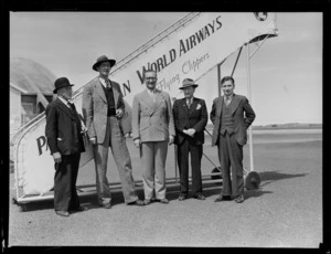 Group portrait of (L to R) Misters John Gaffage (Australian movie star), Smith, Postle and Waite, in front of a Pan American Airways boarding steps, Whenuapai Airfield, Auckland