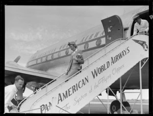 Portrait of Pan American Airways stewardess Pat Hirons on PAA plane boarding steps with unidentified ground staff, Whenuapai Airfield, Auckland