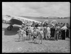 Crowd of unidentified people in front of NAC mail plane 'Kahu' for the opening ceremony of the Northland Air Service at Onerahi Airport, Whangarei, Northland