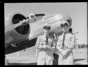 Portrait of (L to R) Commander G R White and 2nd Officer D M Thomas in front of the passenger plane 'Kahu' for the opening ceremony of the Northland Air Service at Onerahi Airport, Whangarei, Northland