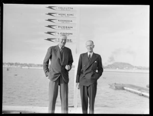 Portrait of (L to R) Sir Arch Jamieson and Colonel C W Salmon standing in front of TEAL sign post, Mechanics Bay Wharf, Auckland Harbour