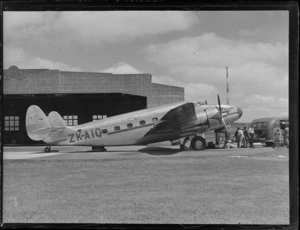 The Lockheed Lodestar ZK-AIQ aeroplane 'Kotuku' in front of Union Airway NZ Ltd hangar with unidentified ground crew, Mangere Airport, Auckland