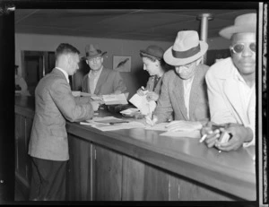 Passengers from PAWA (Pan American World Airways) clipper from America, showing an immigration official checking documents at Whenuapai airport, Auckland