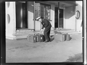 TEA (Tasman Empire Airways) pilot checking baggage outside the TEA reception office, Auckland