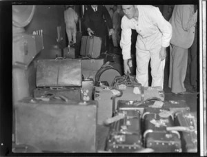 Unidentified baggage handler moving luggage from a Tasman Empire Airways Ltd flight, onto weighing machine, Auckland