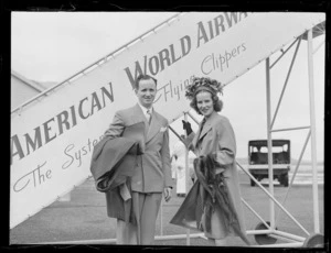 Portrait of Mr and Mrs David and Dora Oppenheimer in front of Pan American Airways plane boarding steps, Whenuapai Airfield, Auckland