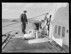 View of unidentified men unloading mail off an RNZAF Sunderland Flying Boat, Mechanics Bay, Auckland City