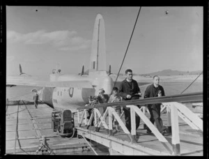 Unidentified passengers and crew on a gangway disembarking an RNZAF Sunderland Flying Boat, Mechanics Bay, Auckland City