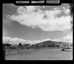 A Tiger Moth bi-plane on a grass runway with houses beyond, Rotorua Aerodrome, Bay of Plenty Region