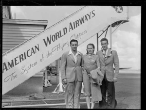 Portrait of (L to R) Mr [Tach] and Mr & Mrs R Wright, American swimmers, in front of Pan American Airways plane boarding steps, Whenuapai Airfield, Auckland