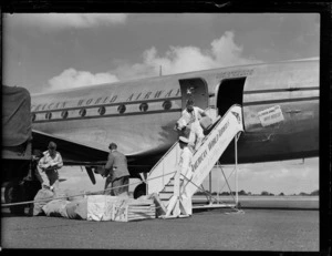 Unidentified ground crew unloading mail from a Pan American Airways Clipper Behring passenger plane, Whenuapai Airfield, Auckland