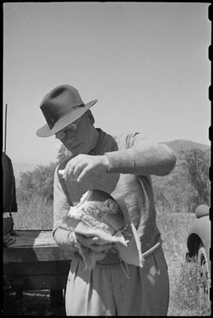 Prime Minister Peter Fraser tries loaf of freshly baked bread while visiting 2 NZ Field Bakery, Italy, World War II - Photograph taken by George Bull