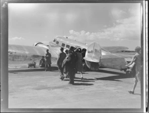Group of unidentified passengers on tarmac alongside Lockheed Electra aeroplane 'Kuaka', [at Union Airways Ltd, Mangere, Auckland?]