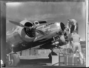 View of unnidentified ground crew working on NZNAC Lockheed Electra 'Kahu' twin engine passenger plane, Mangere Airport, Auckland