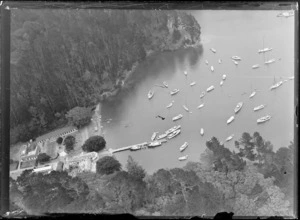 View of an island bush cove and a large building with tennis courts and jetty with yachts moored in front, [Bay of Islands or Hauraki Gulf?]