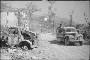 NZ vehicles pass a wrecked enemy vehicle as they advance after the fall of Atina and Belmonte, Italy, World War II - Photograph taken by George Kaye
