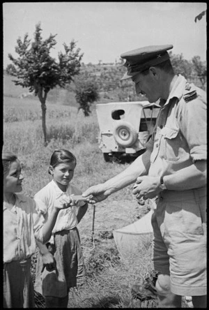 Captain A Simpson gives chocolate to two Italian girls in the artillery lines near Sora, World War II - Photograph taken by George Kaye