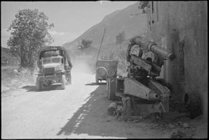 NZ Division vehicle passes abandoned enemy gun on main road through Balsorano in Italy, World War II - Photograph taken by George Kaye
