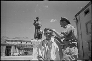 New Zealand soldier having haircut near a religious statue in Sora, Italy, World War II - Photograph taken by George Kaye