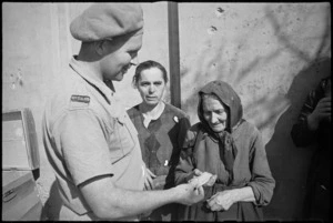 New Zealand soldier gives chocolate to an aged civilian who has returned to Orsogna, Italy, World War II - Photograph taken by George Kaye