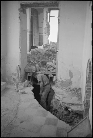 New Zealander investigates German trench in schoolroom at Orsogna, Italy, World War II - Photograph taken by George Kaye