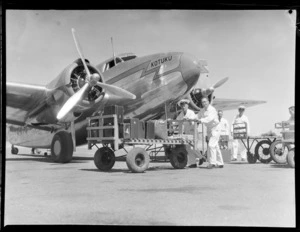 New Zealand National Air Corporation, Rongotai, Wellington, loading staff at work, includes Kotuku aircraft and staff in uniform