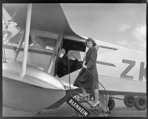 Unidentified female passenger boarding a NZNAC (New Zealand National Airways Corporation), De Havilland Rapide aircraft, Tikaka, Rongotai, Wellington, travelling to Blenheim