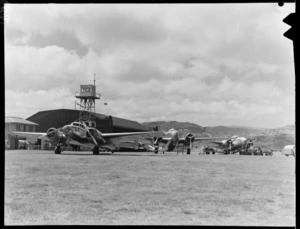 New Zealand National Airways Corporation Lockheed aeroplanes, including 'Koreke', ZK-ALH, at Rongotai Airport, Wellington, including air traffic control tower
