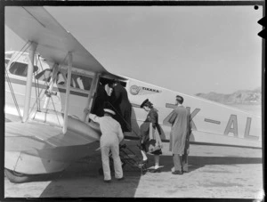 Group of unidentified passengers boarding New Zealand National Airways Corporation de Havilland Dragon Rapide aeroplane 'Tikaka', bound for Blenheim, at Rongotai Airport, Wellington